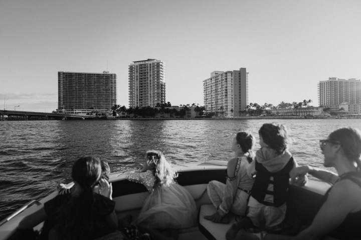 People on boat looking at cityscape with high-rise buildings across the water.